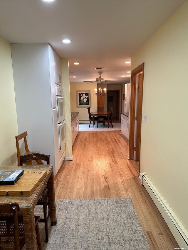 hallway featuring light hardwood / wood-style floors, an inviting chandelier, and a baseboard heating unit