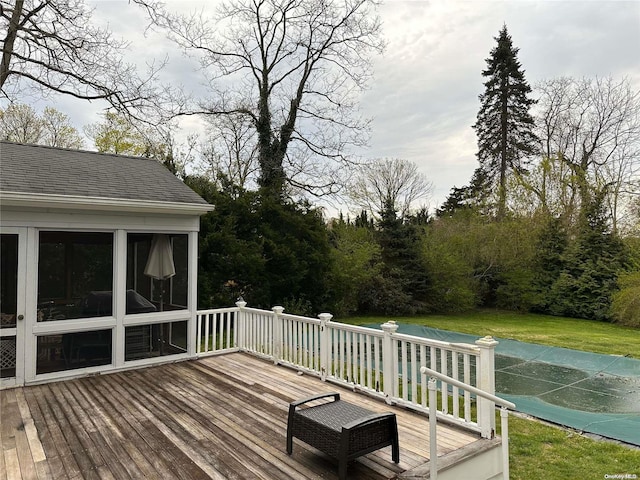 deck featuring a sunroom and a lawn