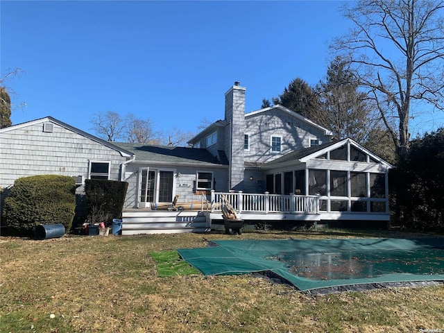 back of property with a sunroom, a swimming pool side deck, and a yard