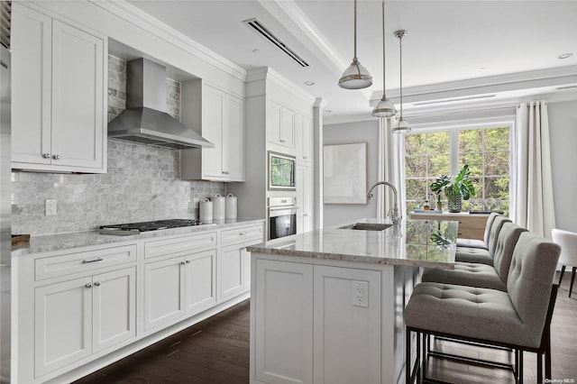 kitchen with wall chimney range hood, sink, appliances with stainless steel finishes, dark hardwood / wood-style flooring, and light stone counters