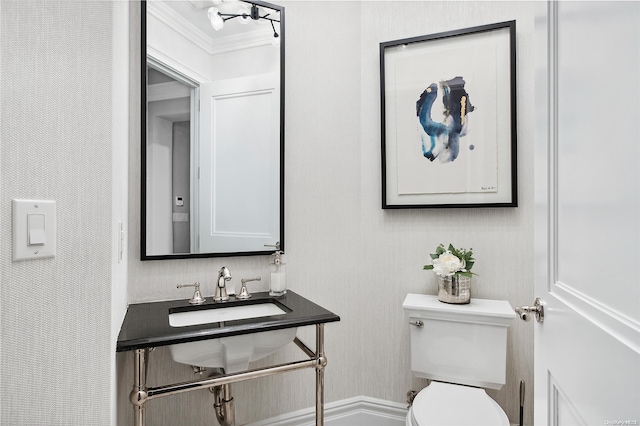 bathroom with toilet, crown molding, and sink