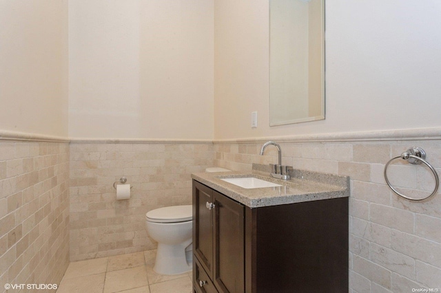 bathroom featuring tile patterned flooring, vanity, toilet, and tile walls