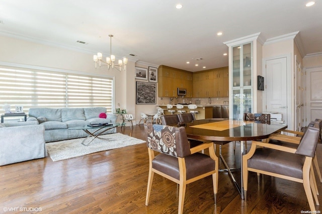 dining room with crown molding, wood-type flooring, and an inviting chandelier