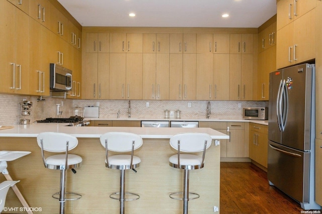 kitchen with a kitchen breakfast bar, backsplash, dark hardwood / wood-style flooring, and stainless steel appliances