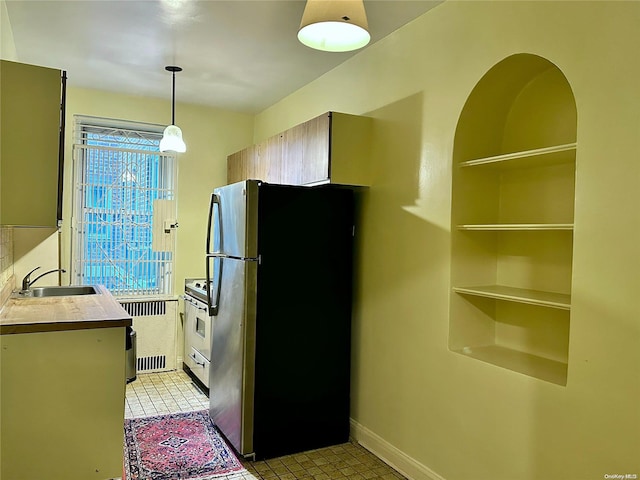 kitchen with pendant lighting, sink, light tile patterned floors, radiator heating unit, and stainless steel appliances