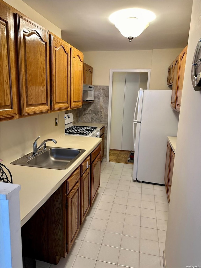 kitchen with backsplash, white appliances, sink, and light tile patterned floors