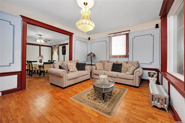 living room featuring ceiling fan with notable chandelier and hardwood / wood-style flooring