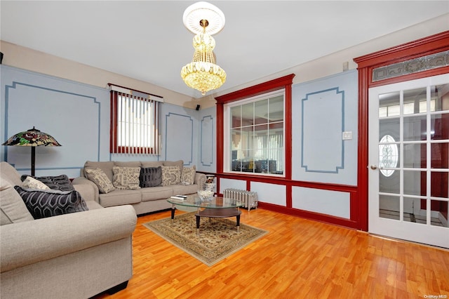 living room featuring radiator, hardwood / wood-style floors, and a notable chandelier