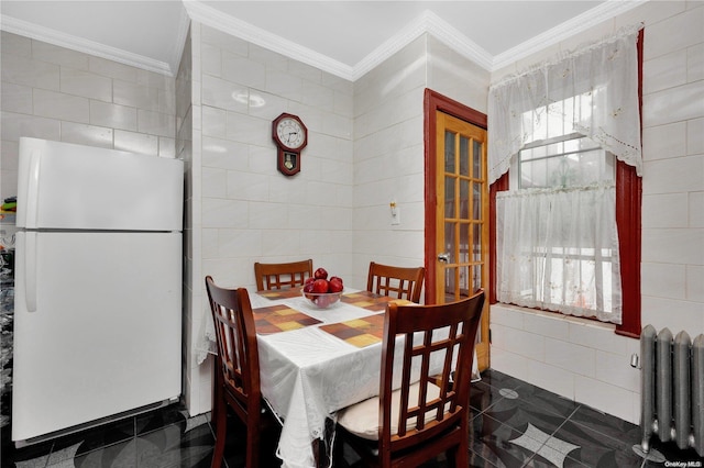 dining area with crown molding, radiator heating unit, and tile walls