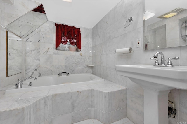 bathroom featuring tiled bath, sink, and tile walls