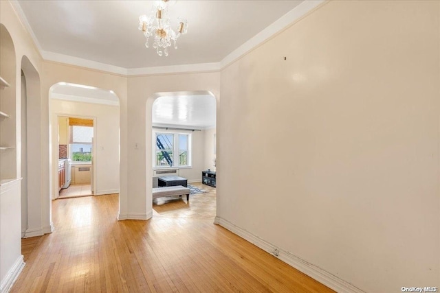 hallway featuring a chandelier, crown molding, and light hardwood / wood-style floors