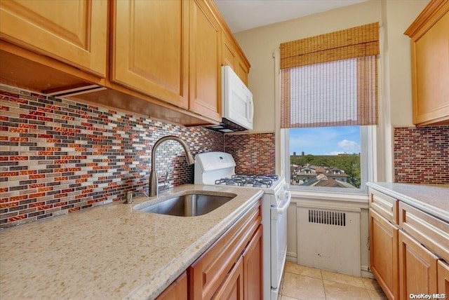 kitchen featuring tasteful backsplash, light stone counters, sink, and white appliances