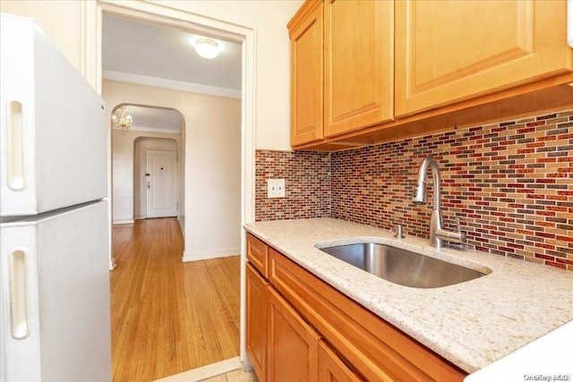 kitchen featuring sink, light stone counters, white refrigerator, backsplash, and light hardwood / wood-style floors