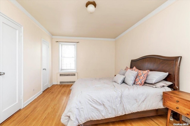 bedroom with radiator, ornamental molding, and light wood-type flooring