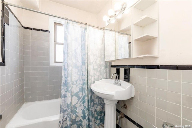 bathroom with sink, shower / bath combo, and tile walls