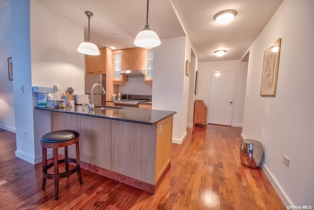 kitchen featuring sink, hanging light fixtures, stainless steel fridge, light wood-type flooring, and kitchen peninsula