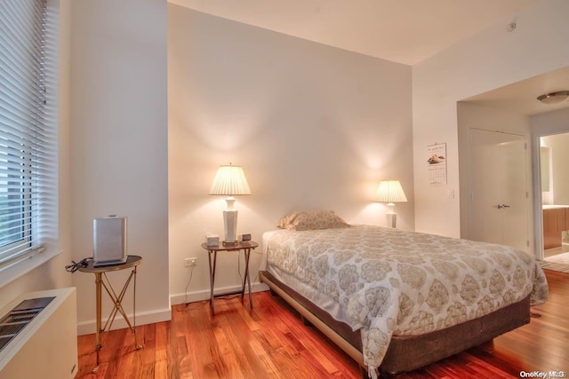 bedroom with hardwood / wood-style floors and ensuite bath