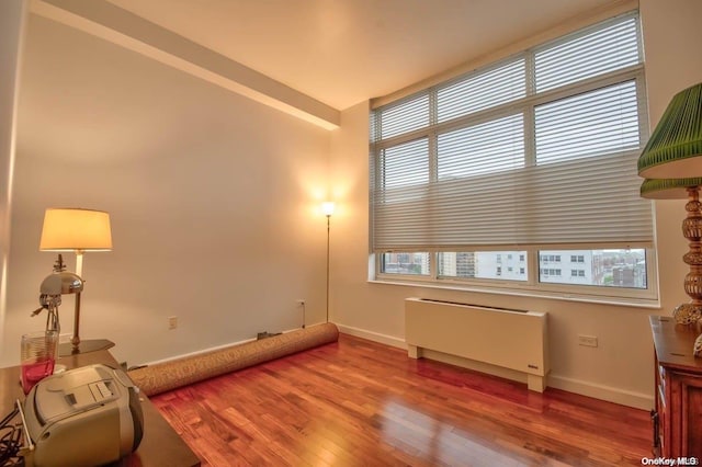 living area featuring a wealth of natural light, wood-type flooring, and radiator