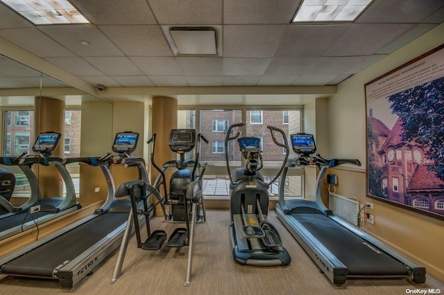 exercise room with a drop ceiling, carpet floors, and plenty of natural light