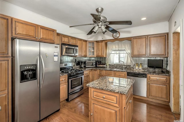 kitchen with wood-type flooring, appliances with stainless steel finishes, a kitchen island, and sink