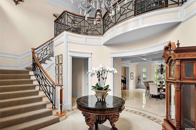 foyer entrance with a chandelier, a towering ceiling, and ornamental molding