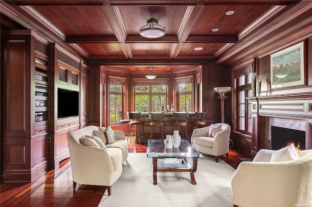 living area featuring wooden ceiling, coffered ceiling, wooden walls, a fireplace, and ornamental molding