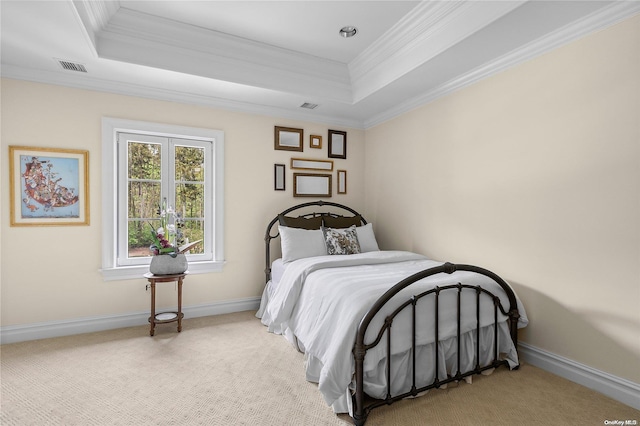 carpeted bedroom with ornamental molding and a tray ceiling