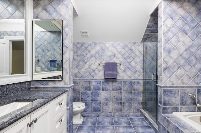 full bathroom featuring tile patterned floors, vanity, tile walls, independent shower and bath, and toilet