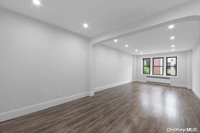 empty room featuring radiator heating unit and dark wood-type flooring