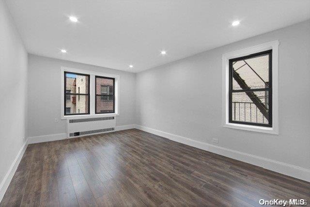 empty room with dark hardwood / wood-style floors and radiator