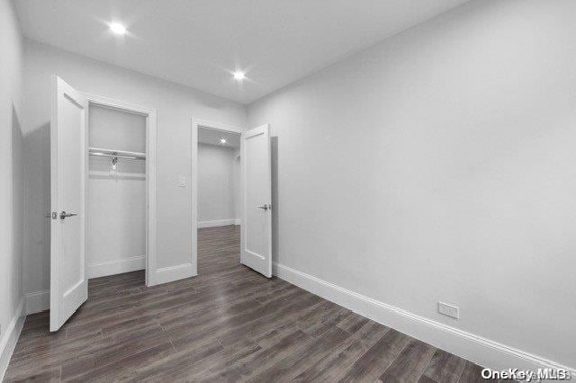 unfurnished bedroom with dark hardwood / wood-style flooring and a closet