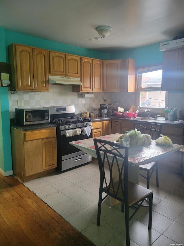 kitchen with light hardwood / wood-style floors, sink, appliances with stainless steel finishes, and tasteful backsplash