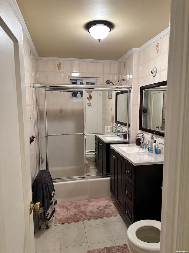 full bathroom featuring combined bath / shower with glass door, vanity, crown molding, tile walls, and tile patterned flooring