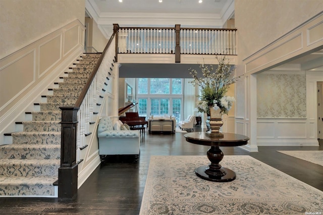 interior space featuring hardwood / wood-style floors, a towering ceiling, and crown molding