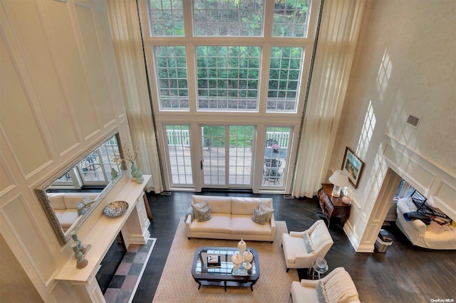 living room with dark hardwood / wood-style flooring and a towering ceiling