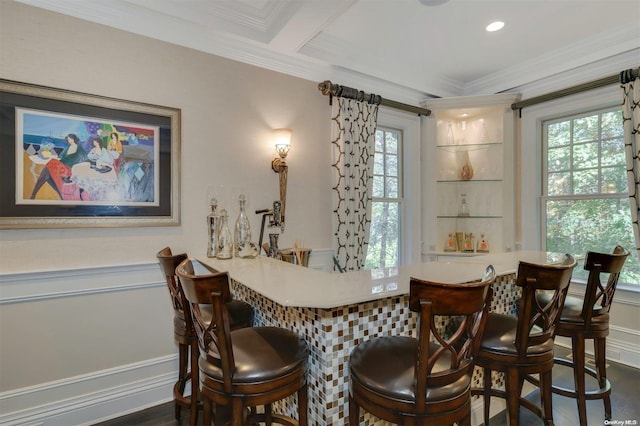 dining area featuring bar area, dark wood-type flooring, crown molding, and a healthy amount of sunlight