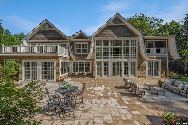 rear view of property featuring french doors, a patio, a balcony, and an outdoor hangout area