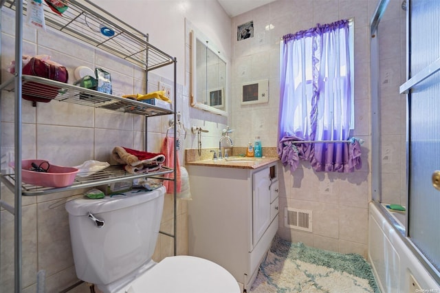 full bathroom with shower / bath combination with glass door, vanity, and tile walls