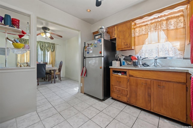 kitchen with ceiling fan, light tile patterned floors, sink, and stainless steel refrigerator