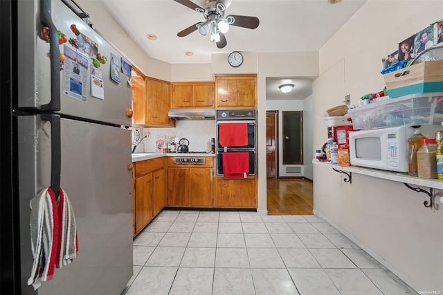 kitchen featuring tasteful backsplash, light tile patterned floors, stainless steel appliances, and ceiling fan