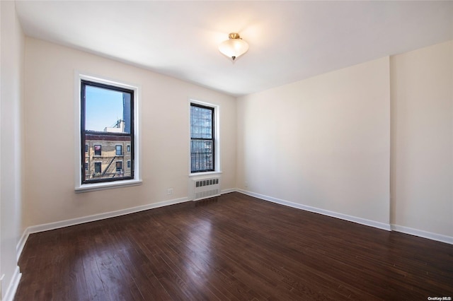 spare room featuring radiator heating unit and dark hardwood / wood-style floors