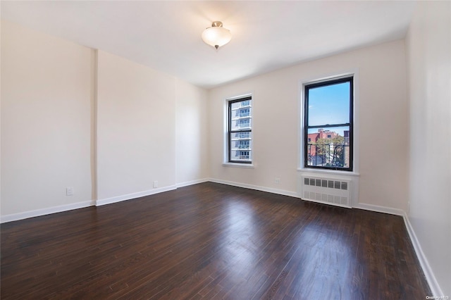 spare room featuring radiator heating unit and dark wood-type flooring