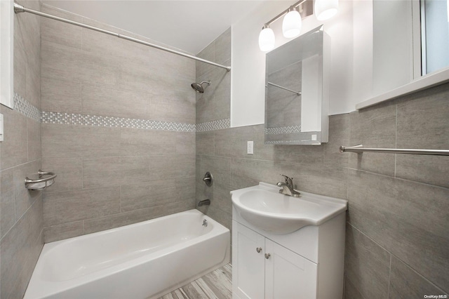 bathroom featuring vanity, tiled shower / bath combo, and tile walls