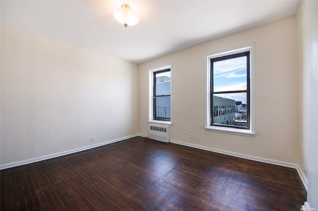 spare room featuring dark hardwood / wood-style floors and radiator