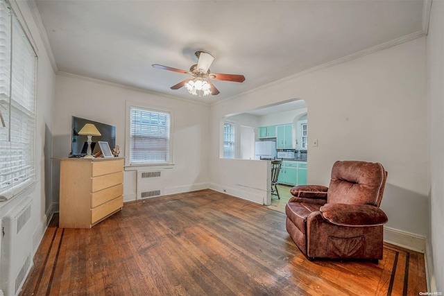 sitting room featuring ceiling fan, wood-type flooring, radiator heating unit, and crown molding