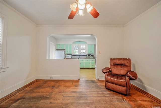 living area with ceiling fan, wood-type flooring, and crown molding