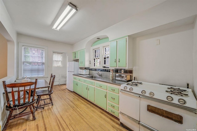 kitchen with green cabinets, sink, white appliances, and light wood-type flooring