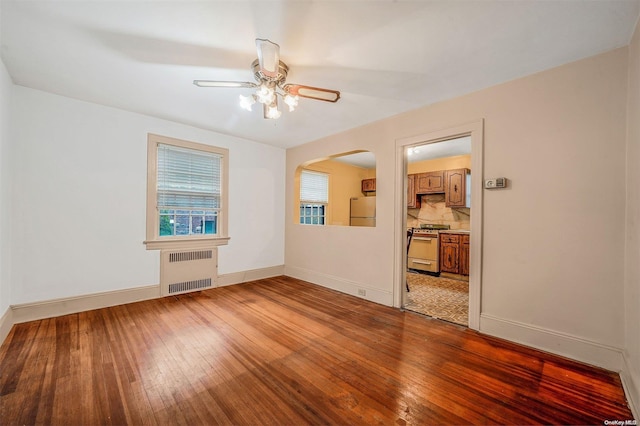 unfurnished room with radiator, ceiling fan, and wood-type flooring