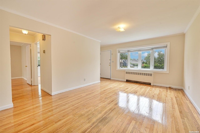 empty room featuring radiator, crown molding, and light hardwood / wood-style flooring