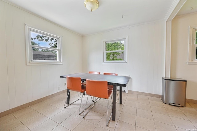 dining room featuring wood walls, light tile patterned floors, and crown molding